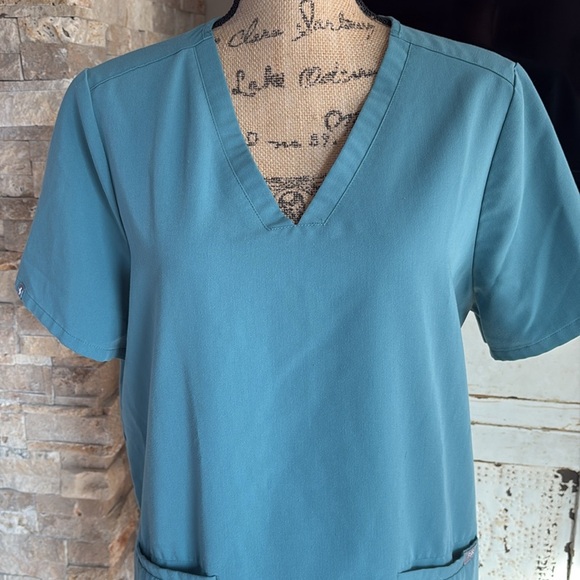 FIGS v-neck short sleeve two front pocket scrub shirt in a blue green color - Picture 2 of 16